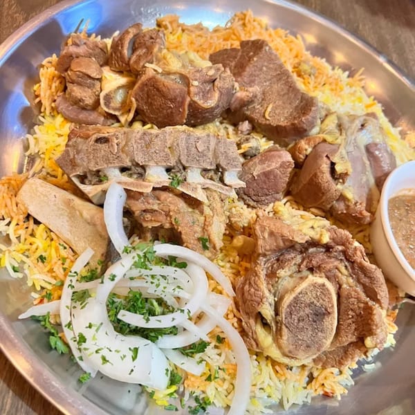 Bab Al-Yemen's mandi, a large platter of spiced rice and tender lamb, garnished with onions and parsley.